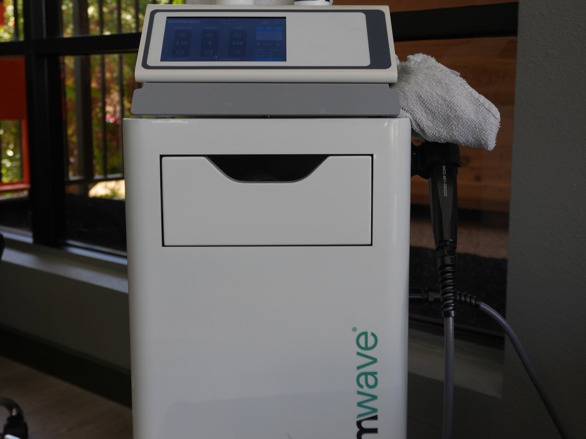 The StemWave console at WLF Club with its control screen lit and the handpiece resting on its hose.